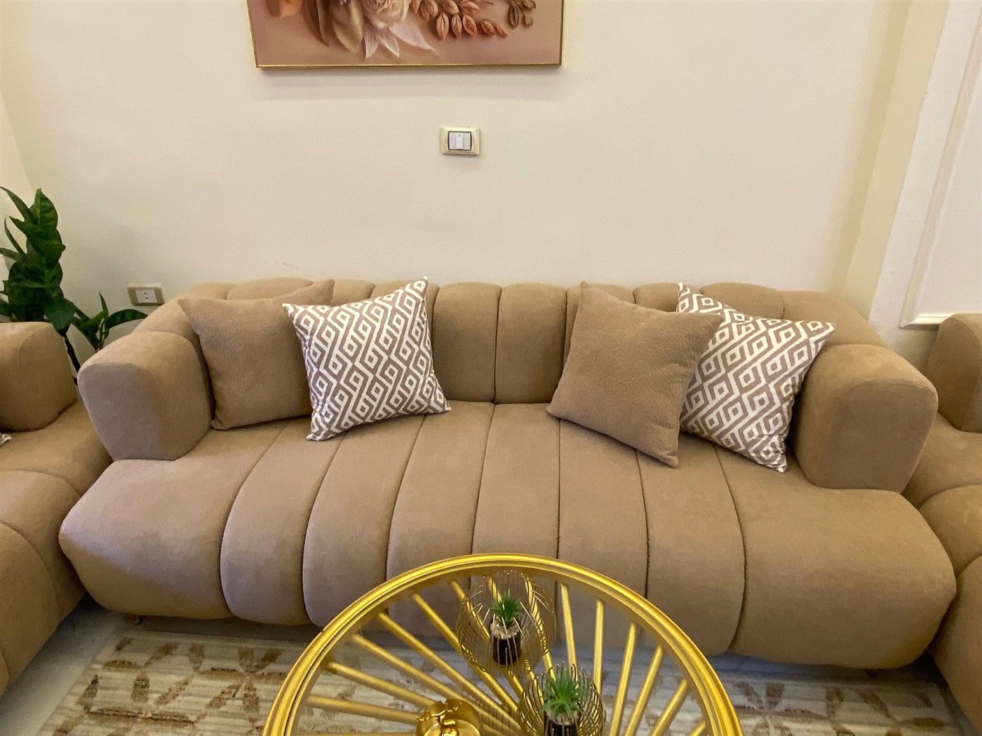 Channel-tufted beige sofa delivered in a client's living room, gold coffee table in front